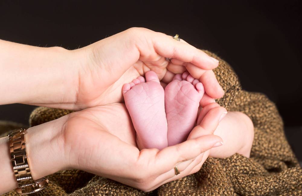 Babyfüße in den Händen der Eltern